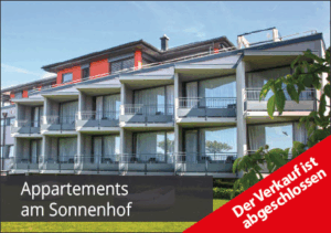 Modern apartment building with balconies and large windows, set in a green area. Text reads Appartements am Sonnenhof and a red banner says Der Verkauf ist abgeschlossen (The sale is complete).